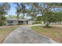 Lovely single-story home featuring a curved driveway, mature trees, and an attached garage, set back from the street at 990 W French Ave, Orange City, FL 32763
