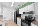 Modern kitchen with white cabinets, granite countertops, black appliances, and plenty of storage space at 990 W French Ave, Orange City, FL 32763