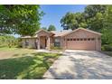 Inviting single-story brick home with a long driveway and mature landscaping in a lush green setting at 1120 W Glen Falls Rd, Deland, FL 32720
