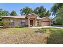 Attractive single-story brick home featuring a manicured lawn, front garden beds and an attached garage at 1120 W Glen Falls Rd, Deland, FL 32720