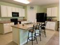 Bright kitchen features white cabinets, black appliances, an island with seating, and tile flooring at 119 Fishermans Cove Dr, Edgewater, FL 32141