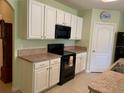 Updated kitchen boasts white cabinetry, black appliances, tile floors, and laminate countertops at 119 Fishermans Cove Dr, Edgewater, FL 32141