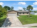 Charming single-story home featuring a lush green lawn, a palm tree, and an attached garage at 1191 Tracy Dr, Port Orange, FL 32129