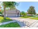 Beautiful home featuring a well-manicured lawn, trees, and a two-car garage on a sunny day at 12079 Alder Branch Loop, Orlando, FL 32824