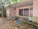 Overgrown back porch area featuring broken windows, piles of leaves, and damaged exterior walls at 16880 Se 63Rd Ln, Ocklawaha, FL 32179