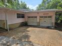 Exterior shot of the garage with a driveway leading up to two doors and a light pink stucco exterior at 16880 Se 63Rd Ln, Ocklawaha, FL 32179