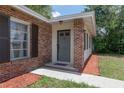 Close-up of a brick-accented front entrance with a gray front door, outdoor lighting, and a well-maintained walkway at 2842 English Dr, Deltona, FL 32738