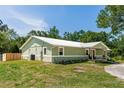 Side view of a single-story house showcasing green paint, a white metal roof, and well-maintained landscaping at 2953 Sled Rd, Christmas, FL 32709