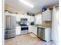 Modern kitchen with stainless steel appliances, white cabinets, granite countertops, and hardwood flooring at 2978 Greynolds St, Deltona, FL 32738
