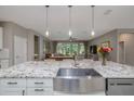 Open-concept kitchen featuring a large island, stainless steel sink, and pendant lighting, seamlessly flowing into the living area at 3026 Adrian Dr, Ormond Beach, FL 32174