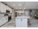 Bright kitchen with white cabinets, stainless steel appliances, granite countertops, and a large center island with barstool seating at 3026 Adrian Dr, Ormond Beach, FL 32174