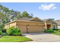 Side view of a tan home with a three car garage showing the driveway, lawn, and some landscaping at 320 W Victoria Trails Blvd, Deland, FL 32724