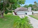 View of the home with an attached two-car garage, long driveway and well-maintained lawn at 718 Sleepy Hollow Dr, Port Orange, FL 32127