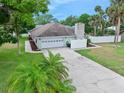 View of the home with an attached two-car garage, long driveway and well-maintained lawn at 718 Sleepy Hollow Dr, Port Orange, FL 32127