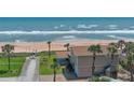 Beach home with private access to the sandy beach and ocean, complemented by palm trees at 8 Ocean Dunes Dr, Ormond Beach, FL 32176