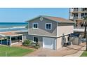 Beach home with a two-car garage, brick-paved driveway, manicured grass, and a covered outdoor bar area at 8 Ocean Dunes Dr, Ormond Beach, FL 32176
