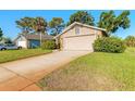 A tan colored home featuring a two-car garage, a clean driveway, and a green lawn at 929 N Lakewood Ter, Port Orange, FL 32127