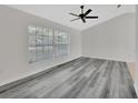 Open living room features a ceiling fan, large window, and stylish gray wood flooring at 1141 Glendale Ave, Deltona, FL 32725