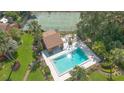 Aerial view of a backyard pool and cabana with lush green surroundings and a tennis court at 115 Oaks Ct # 115, Sanford, FL 32771