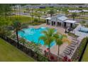 Community pool with a splash pad, lounge chairs, palm trees, and covered seating areas at 1183 Cabot Cliffs Dr, Daytona Beach, FL 32124