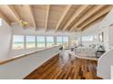 Bright main bedroom with hardwood floors, wood-beamed ceilings, beach views, and access to a balcony at 1209 N Atlantic Ave, New Smyrna Beach, FL 32169