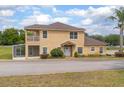 Tan home featuring a balcony, front yard landscaping, and a screened-in porch at 201 Dyson Dr, Deland, FL 32724