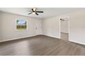 Bright, empty living room features new gray flooring, a ceiling fan, and a large window with a pleasant view at 2106 Umbrella Tree Dr, Edgewater, FL 32141