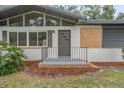 Charming home entrance with modern door, neat landscaping, and painted cinder block at 2215 Lake Ruby Rd, Deland, FL 32724