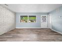 The living room features a brick accent wall, ample natural light, and stylish, easy-to-clean wood-look floors at 2226 Sherwood Dr, South Daytona, FL 32119