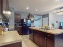 Well-appointed kitchen featuring dark wood cabinetry, stainless steel appliances, tile flooring, and an island with a sink at 2919 Sime St, New Smyrna Beach, FL 32168
