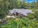 Aerial view of a single-story home with mature trees, lush landscaping, and a brick facade at 4073 N Chinook Ln, Ormond Beach, FL 32174