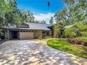 Paver driveway leads to a charming single-story home with a brick facade and mature trees at 4073 N Chinook Ln, Ormond Beach, FL 32174
