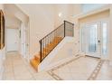 Inviting foyer with tiled floors, a staircase with iron railing, and decorative glass front door at 4427 S Atlantic Ave, Port Orange, FL 32127