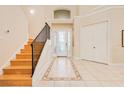 Bright, airy foyer with tiled floors, decorative accents, a staircase, and a decorative glass front door at 4427 S Atlantic Ave, Port Orange, FL 32127