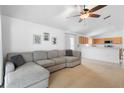 Cozy living room showcasing a comfortable sectional sofa, ceiling fan, and an open view to the kitchen at 700 Spring Cavern Ave, Orange City, FL 32763