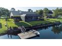 Aerial view of backyard featuring a private dock with boat, screened-in pool, and lush green lawn at 928 Chickadee Dr, Port Orange, FL 32127