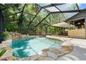 Inviting screened-in pool area with stone accents, a waterfall feature, and an adjacent outdoor bar at 96 Hollow Branch Xing, Ormond Beach, FL 32174