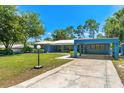 Charming blue single-story home with a manicured lawn and covered carport with curved driveway at 10 Madera Rd, Debary, FL 32713