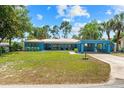 Charming blue single-story home with a manicured lawn and covered carport under bright blue sky at 10 Madera Rd, Debary, FL 32713