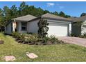 Charming single-story home featuring a two-car garage, a well-manicured lawn, and vibrant landscaping at 112 Lost Ball Dr, Daytona Beach, FL 32124
