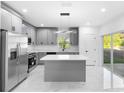 Bright kitchen with grey cabinets, a marble countertop island, modern lighting, stainless steel appliances, and access to the backyard at 1163 W Hancock Dr, Deltona, FL 32725