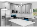 This kitchen showcases gray cabinets, a marble countertop island, stainless steel appliances, and contemporary lighting fixtures at 1163 W Hancock Dr, Deltona, FL 32725