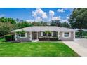 Charming single-story home featuring a well-manicured lawn, mature trees, and a covered parking area at 136 W Gardenia Dr, Orange City, FL 32763