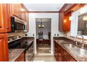 Galley kitchen boasts granite counters, stainless appliances, and cherry wood cabinets at 136 W Gardenia Dr, Orange City, FL 32763