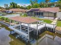 Waterfront property featuring a screened pool, covered patio, and boat lift on the canal at 1520 Stone Trl, Enterprise, FL 32725