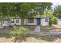 Inviting home featuring white siding, black trim, a blue door, and mature shade trees at 2434 Barbarossa Ave, Deltona, FL 32738