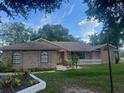 Charming brick home featuring a well-maintained front yard with lush landscaping and a welcoming entrance at 2885 Newmark Dr, Deltona, FL 32738