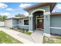 Inviting entryway with a decorative front door, arched entrance, and landscaped garden at 37 Naranja Rd, Debary, FL 32713