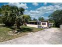 Quaint single-story home with a lush lawn, palm tree accent, and wide concrete driveway at 487 Collins St, Ormond Beach, FL 32174