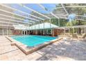 A large screened-in pool is surrounded by brick pavers and outdoor seating area at 712 S Timberlane Dr, New Smyrna Beach, FL 32168